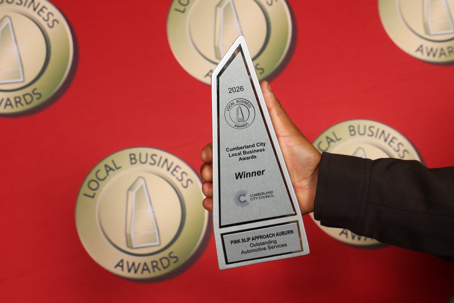 Pink Slip Approach Auburn’s 2026 Cumberland City Local Business Award held against a red awards backdrop