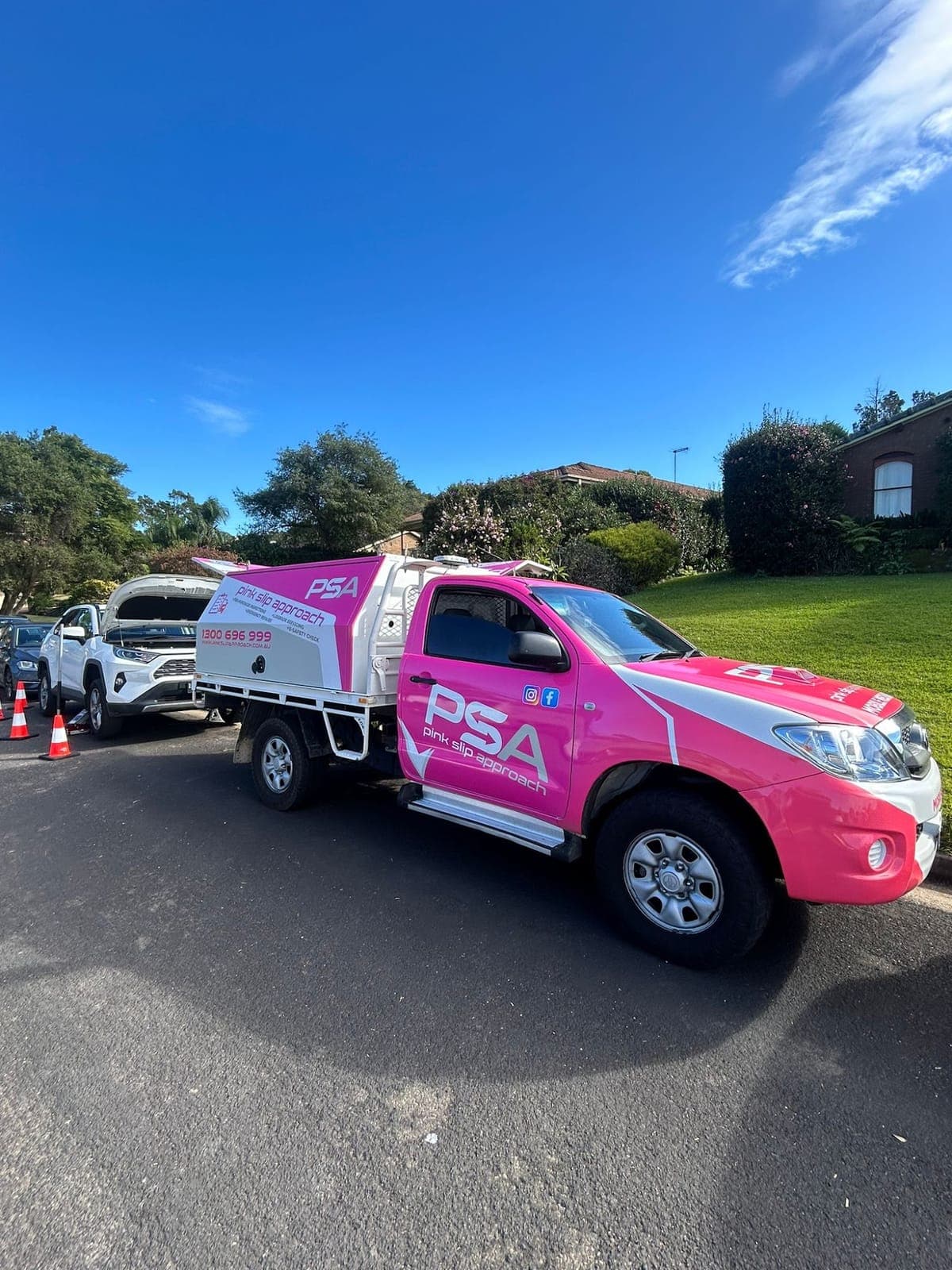 A pink PSA service ute parked in a sunny suburban street
