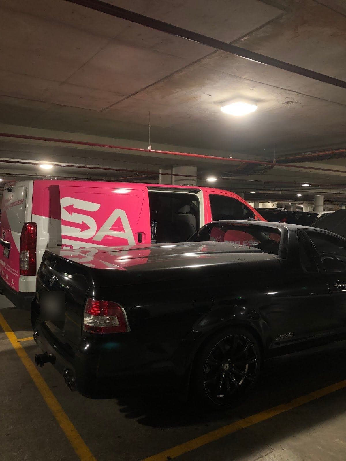 A pink PSA van beside a black ute in an underground car park