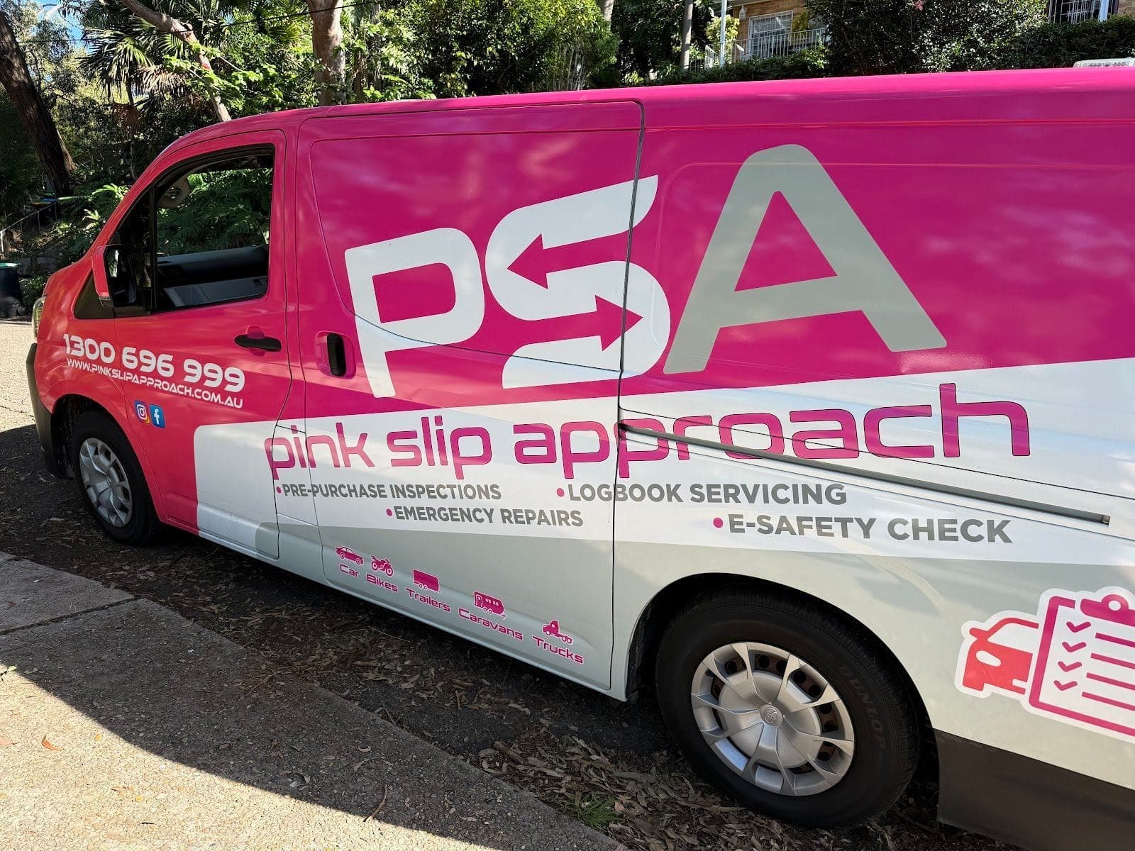 The side of a pink and white PSA van parked under trees