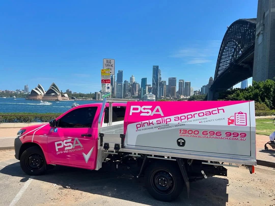 A pink Pink Slip Approach ute parked by Sydney Harbour, with the Opera House and Harbour Bridge behind it