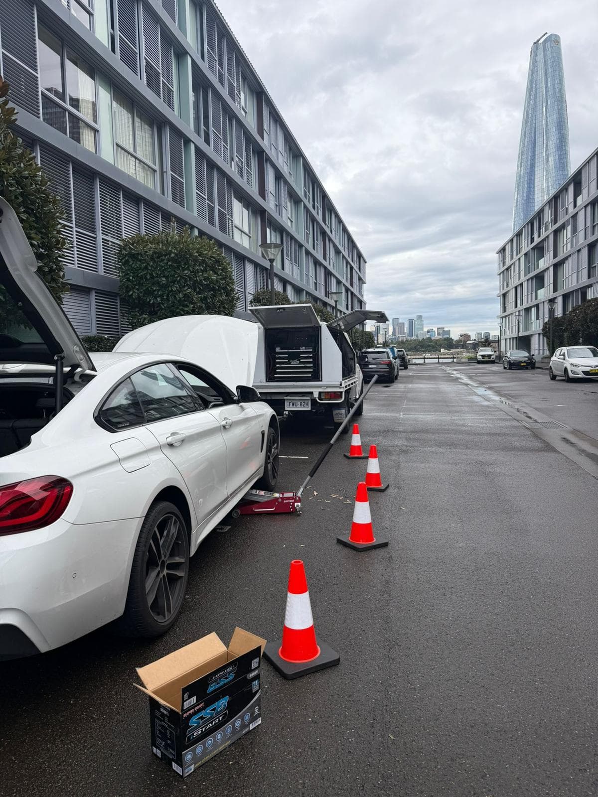 A PSA service ute with its canopy open behind a white BMW on an inner-city street, with cones set out around the job